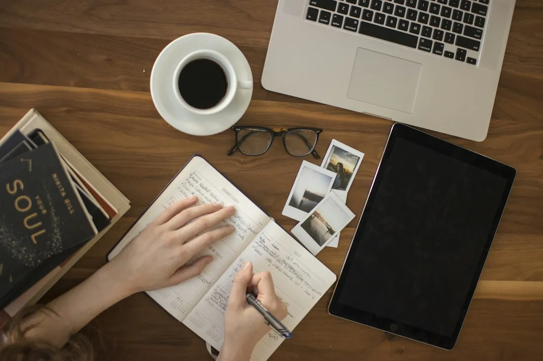 Planning project tasks in a notebook beside a laptop